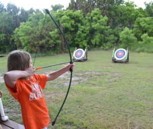 Kid shooting a bow and arrow at archery range